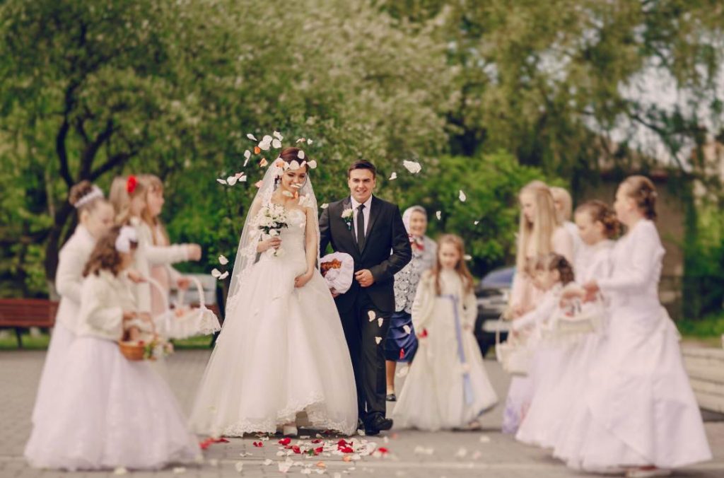 Mariés marchant sous une pluie de pétales entourés de demoiselles d'honneur, illustrant des idées organisation mariage senior 50 ans pour impliquer la famille